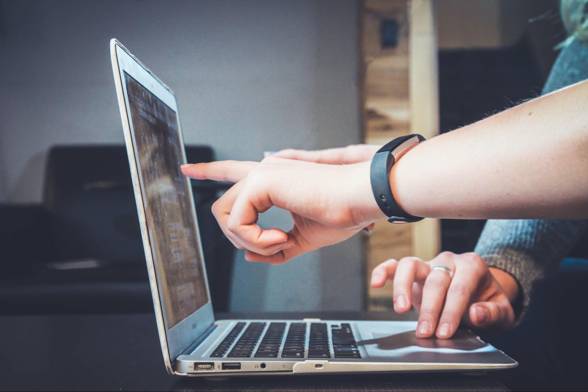 Two people pointing at a laptop screen.