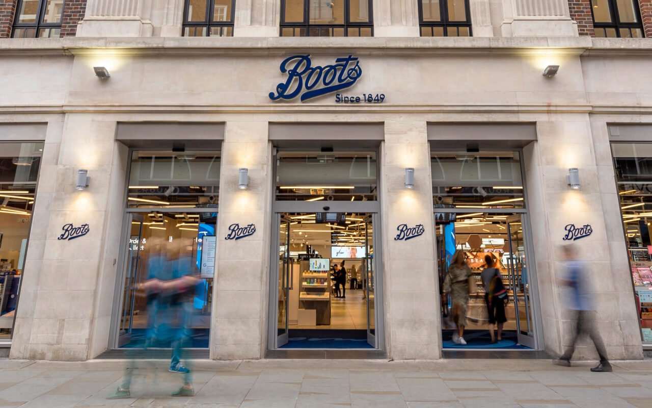 Boots storefront with people passing by.