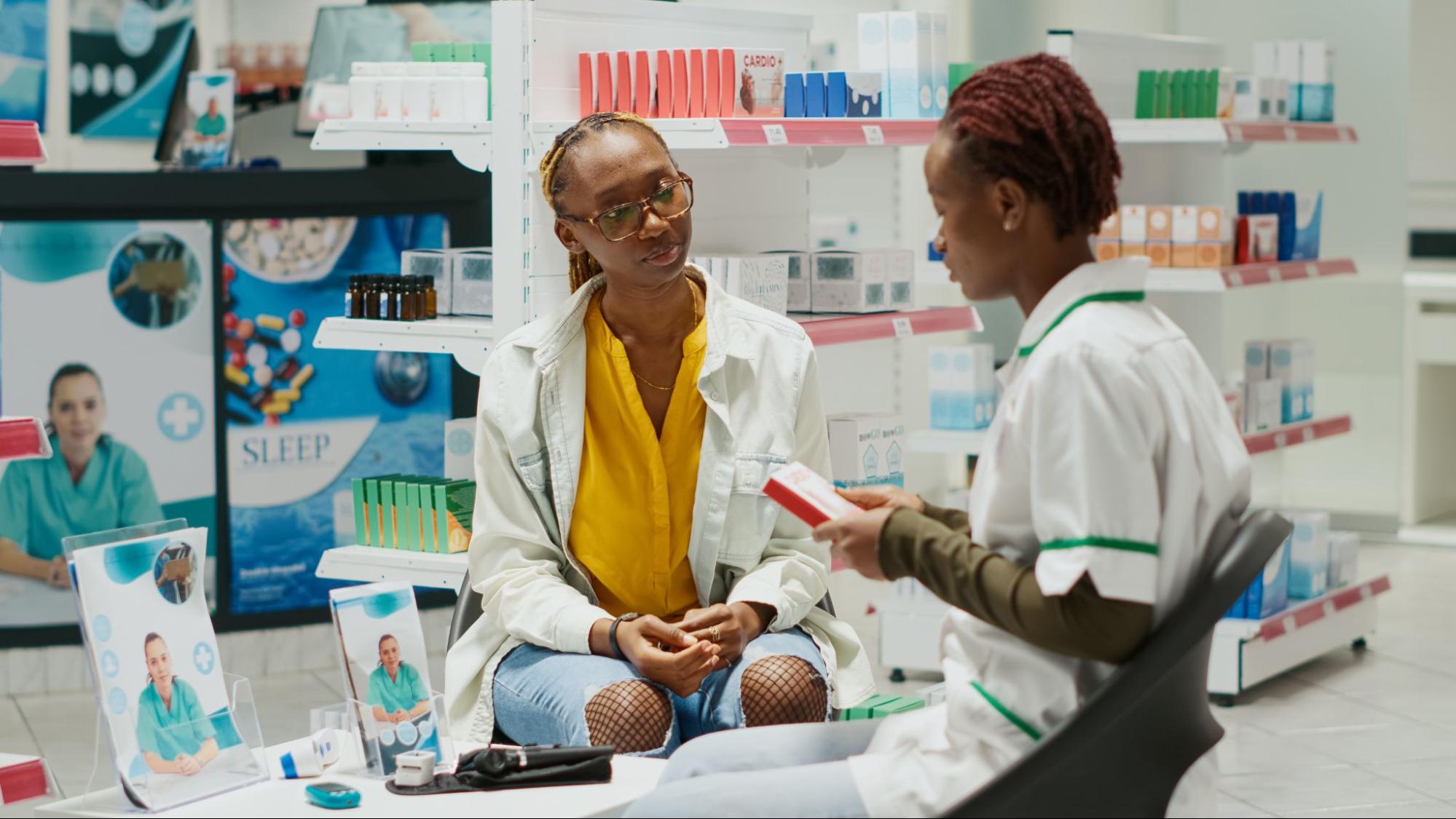 Two pharmacists talking while holding a product.