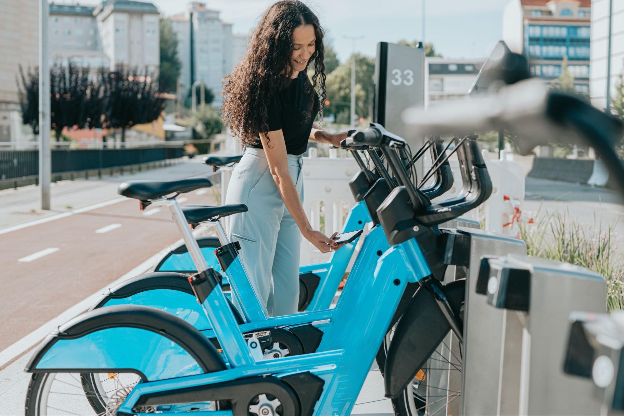 A person standing next to a rental bicycle.