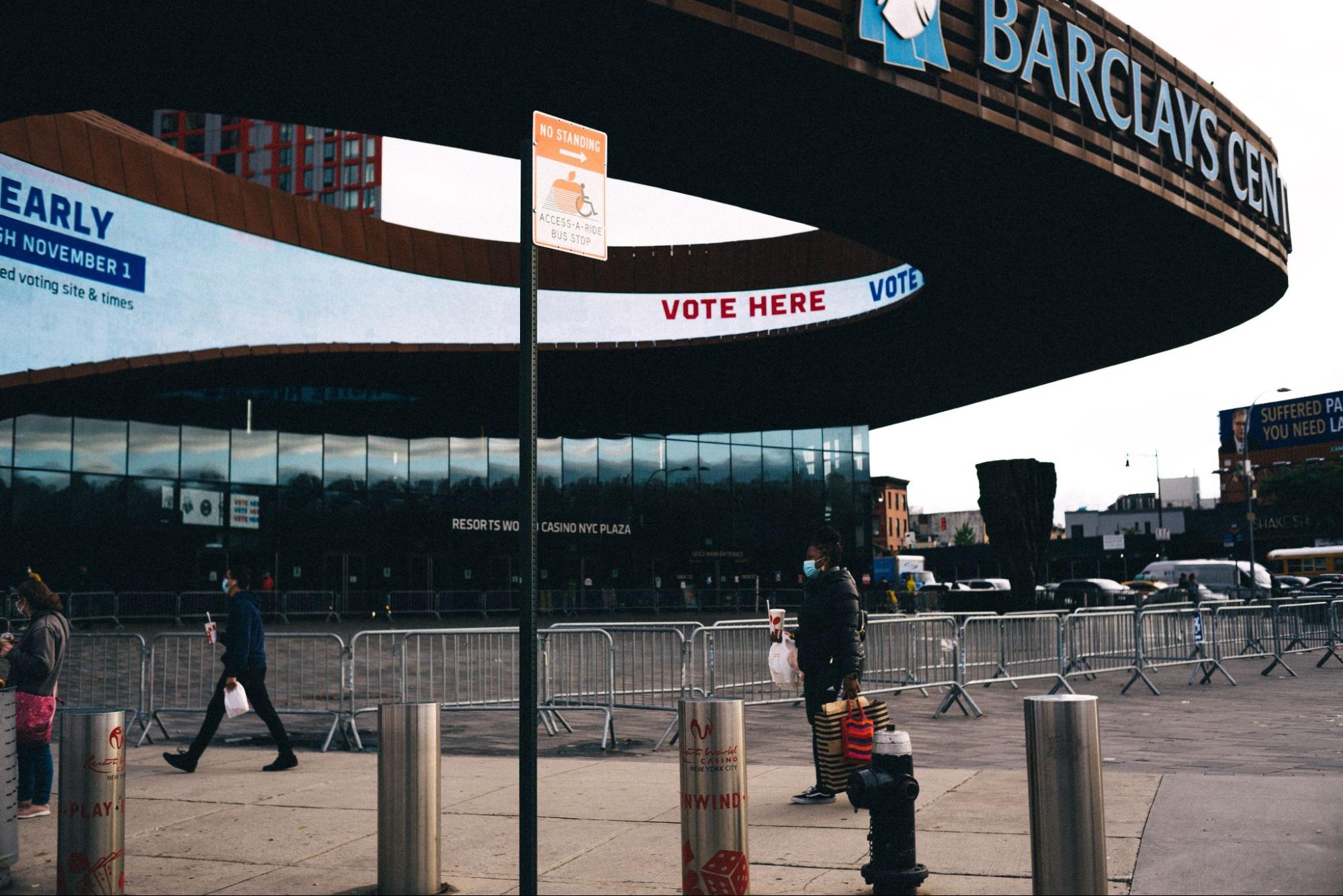 A person standing on a sidewalk next to a Barclays Center.