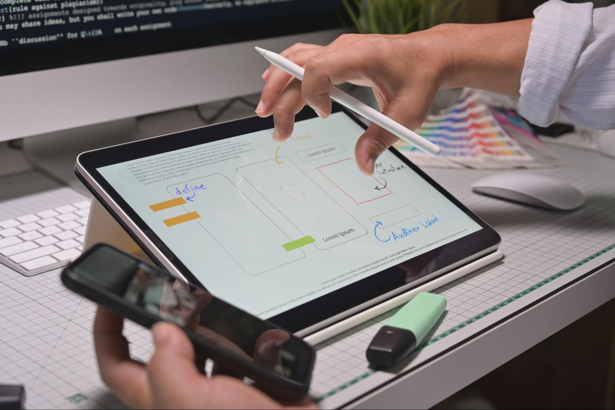 A person using a stylus, a tablet and an iphone for prototyping.