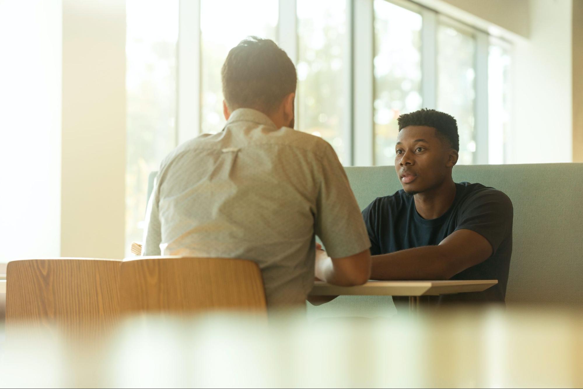 Two people sitting at a table in front of each other.