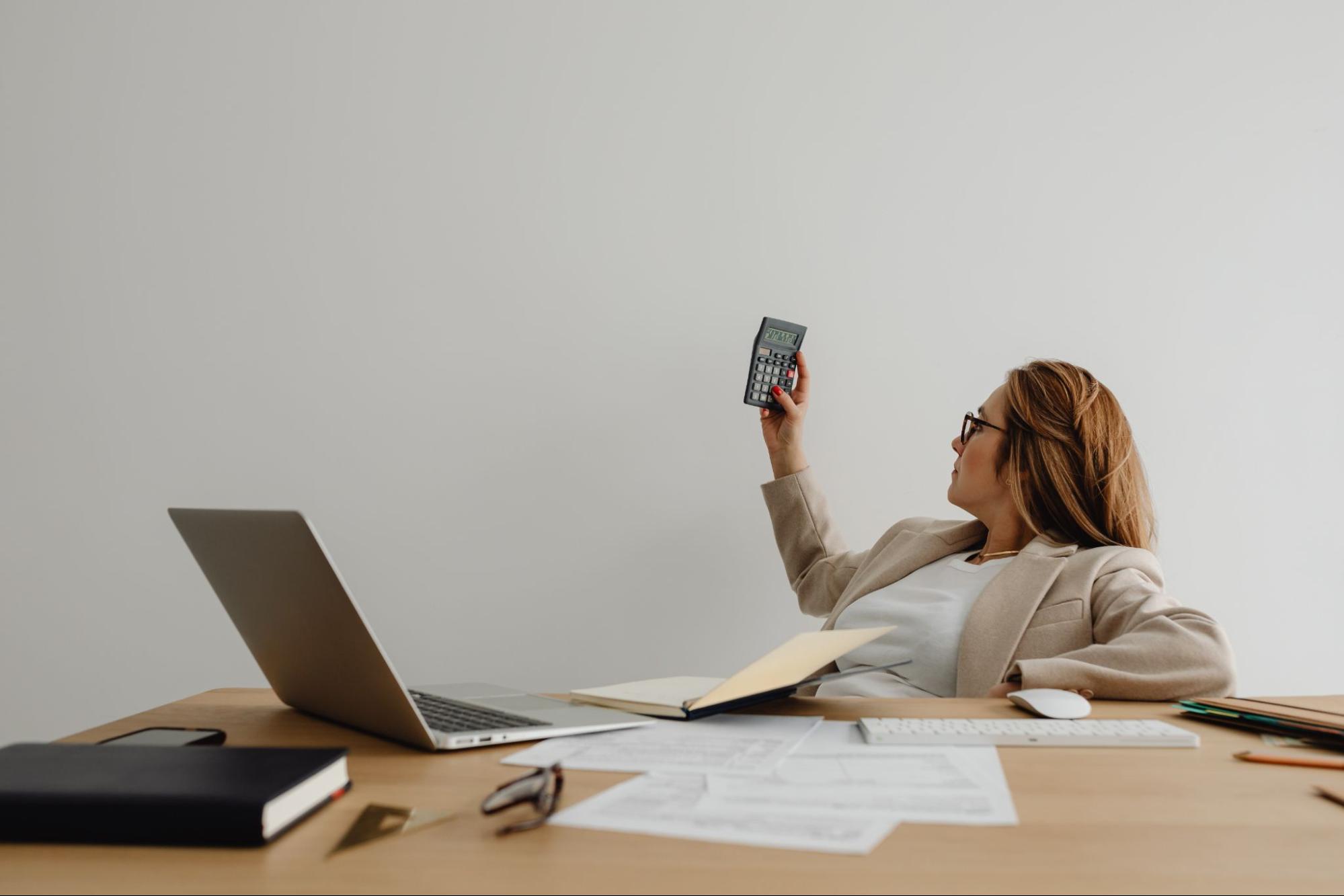 A woman sitting at a desk holding a calculator.