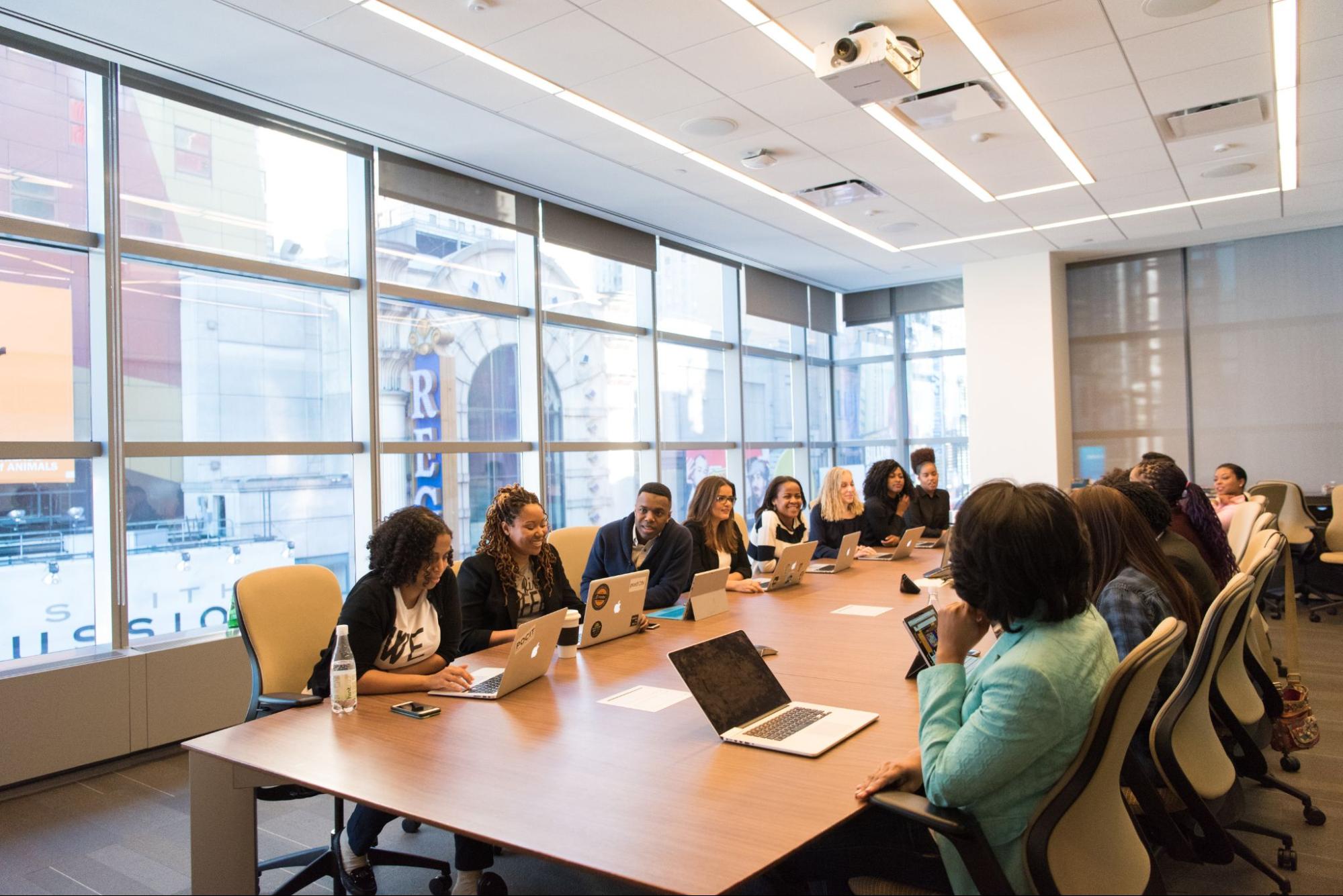 People sitting in a meeting room by a table.