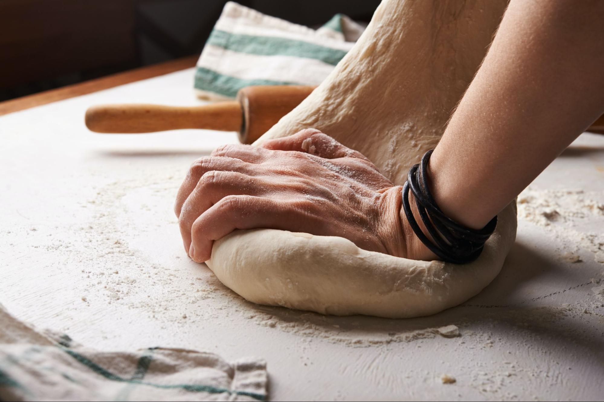 A person kneading dough on a table.