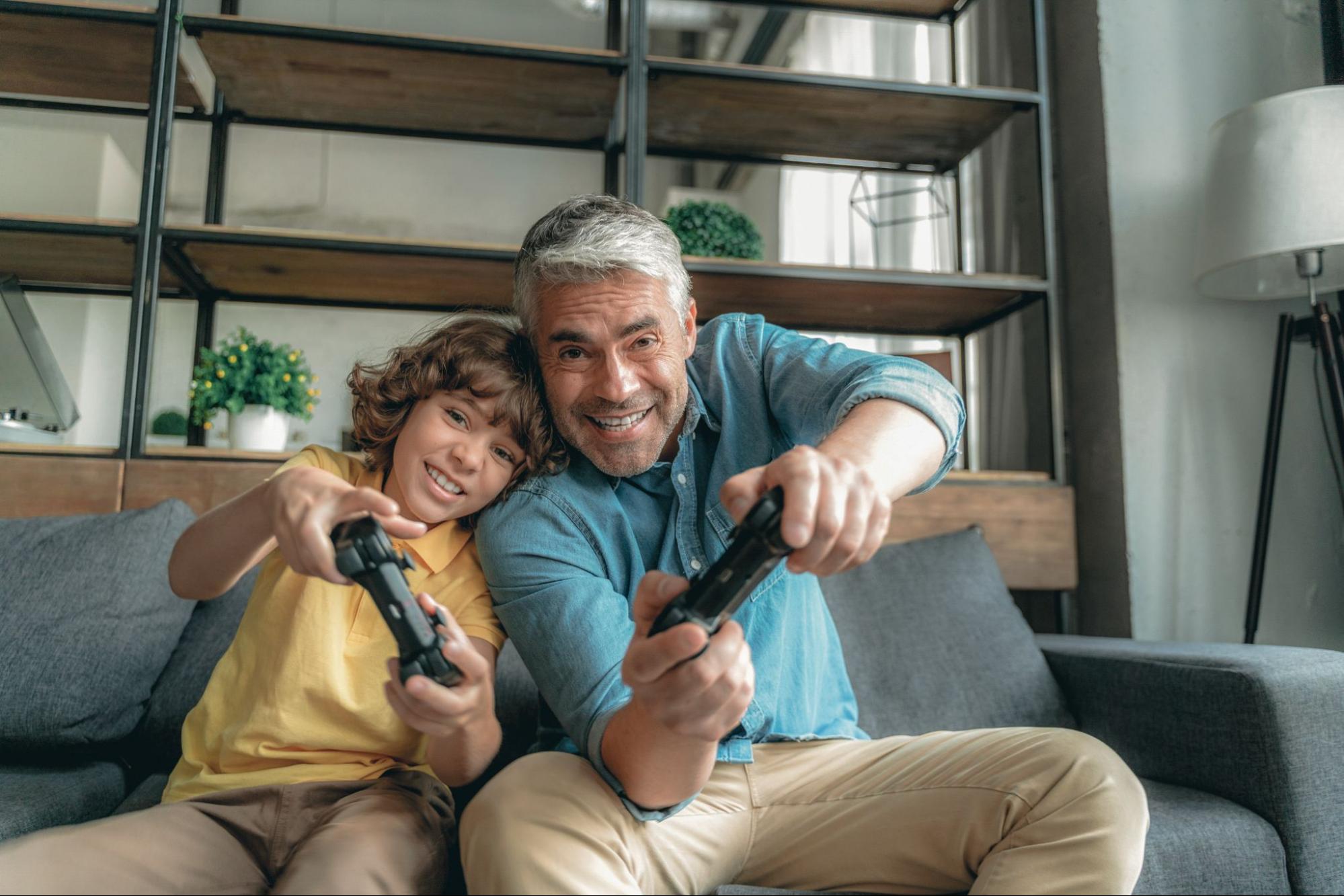 An adult and a child playing a game holding consoles.