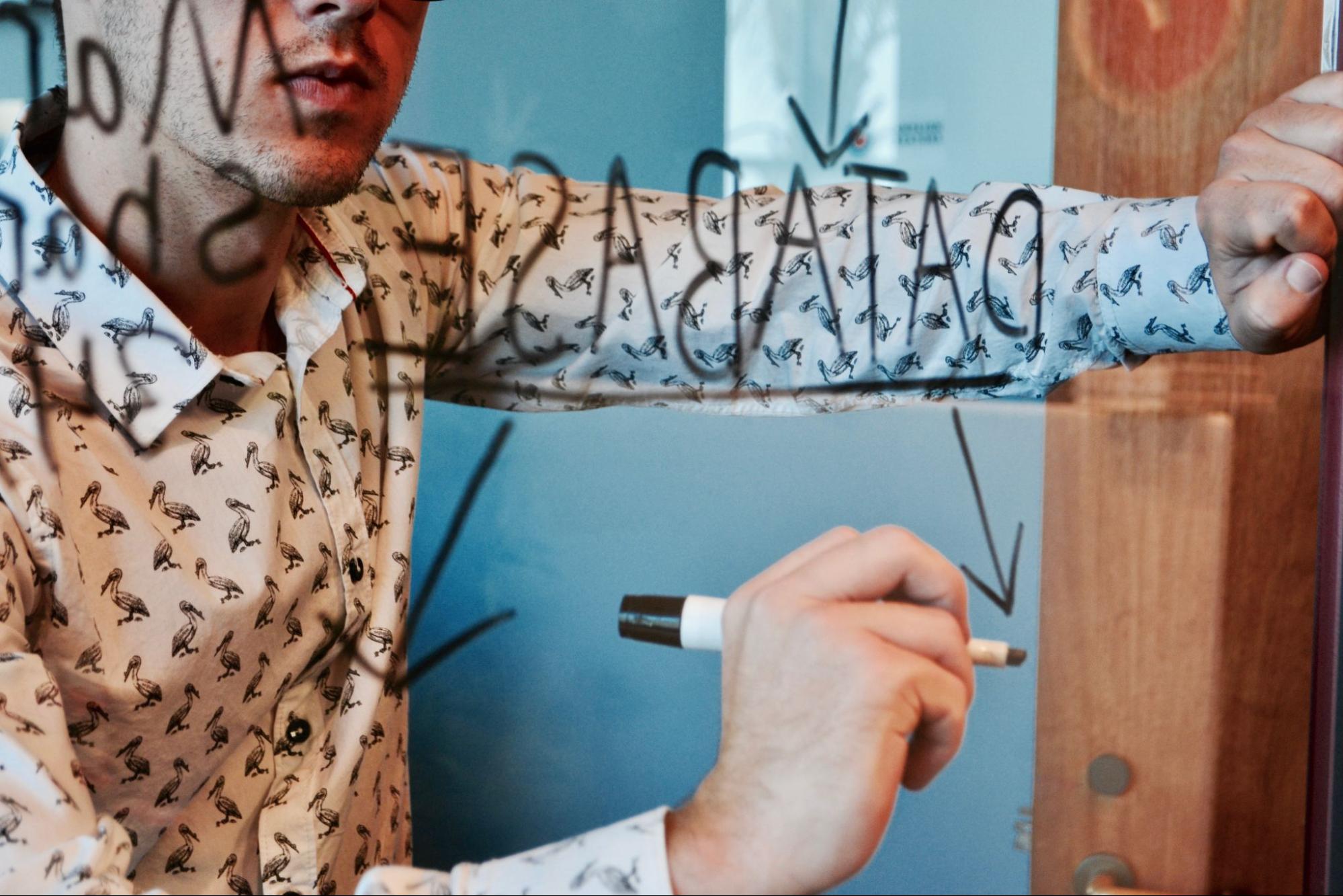 A person writing on a glass board.