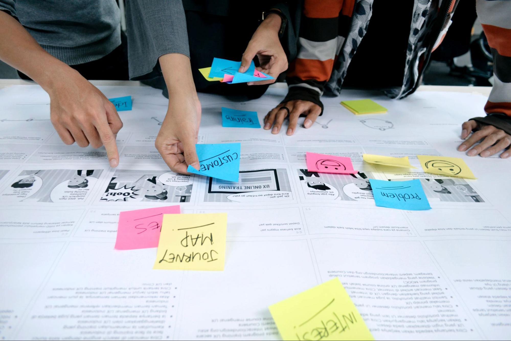 A group of people looking at sticky notes on a table.