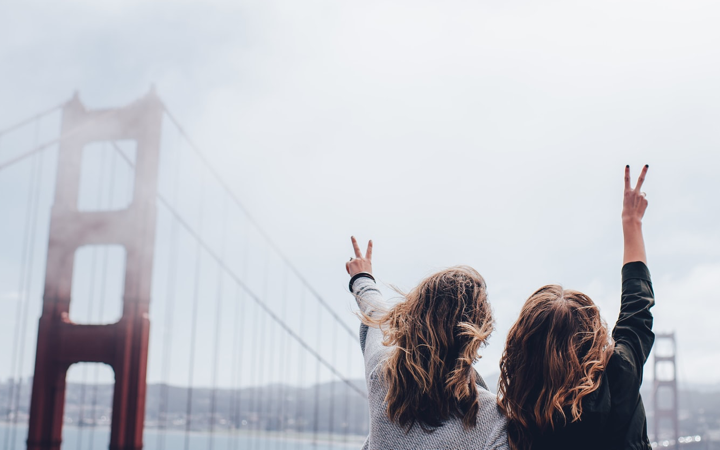 two traveller women standing on a bridge